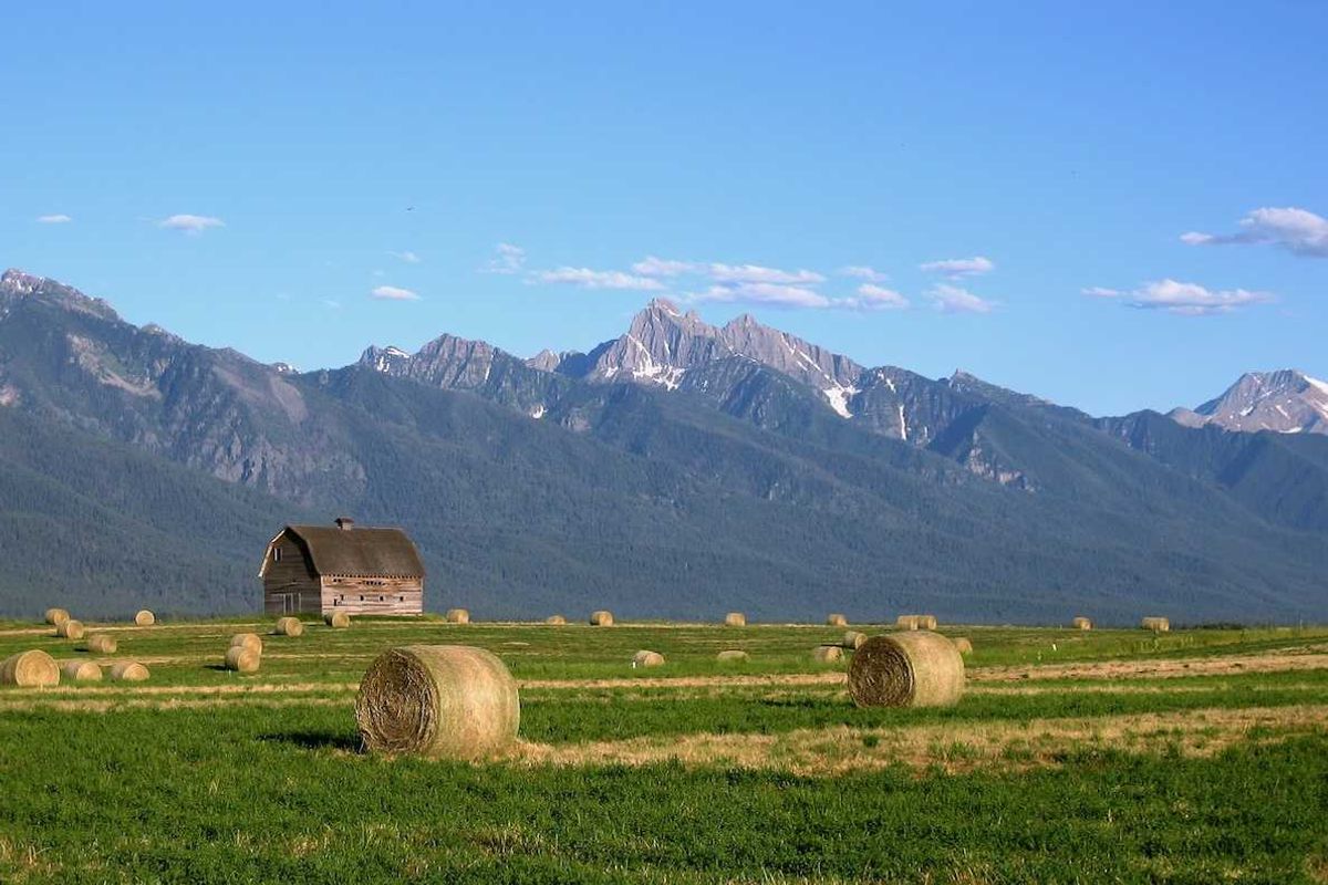 Montana landscape with barn and round-baled hay against snow-capped Rocky Mountains