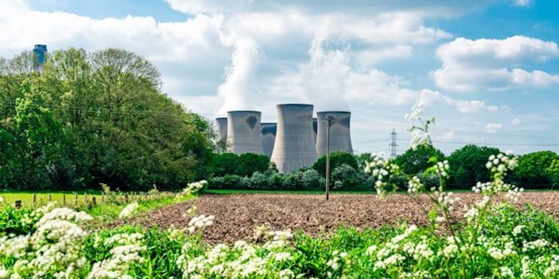 Nuclear reactor towers next to a farm field.