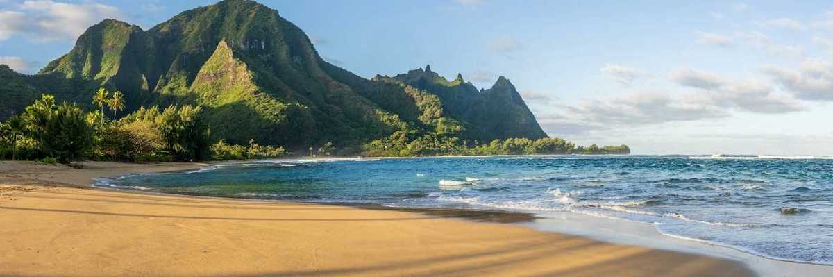 Ocean lapping a sandy South Pacific beach with verdant hills behind