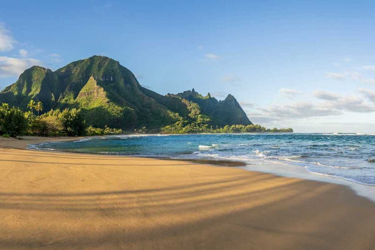 Ocean lapping a sandy South Pacific beach with verdant hills behind