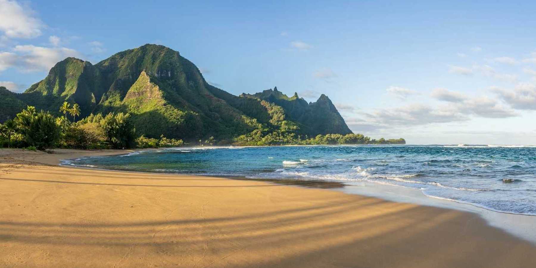 Ocean lapping a sandy South Pacific beach with verdant hills behind