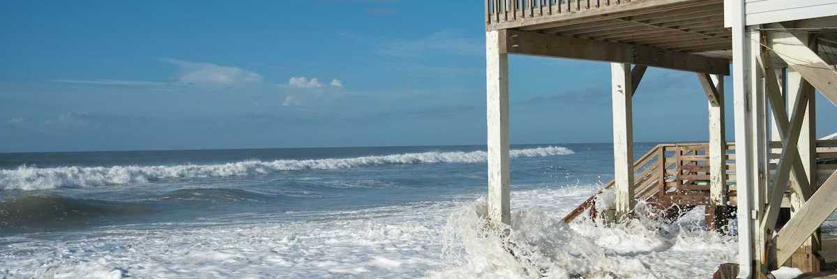 Ocean waves lap against the piers supporting a seaside home