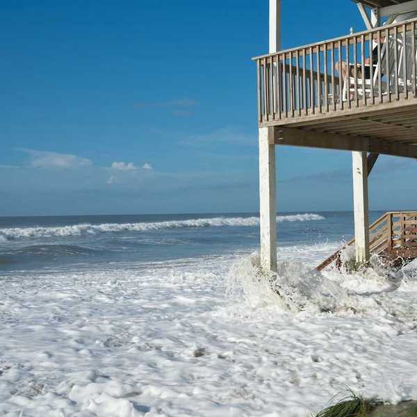Ocean waves lap against the piers supporting a seaside home