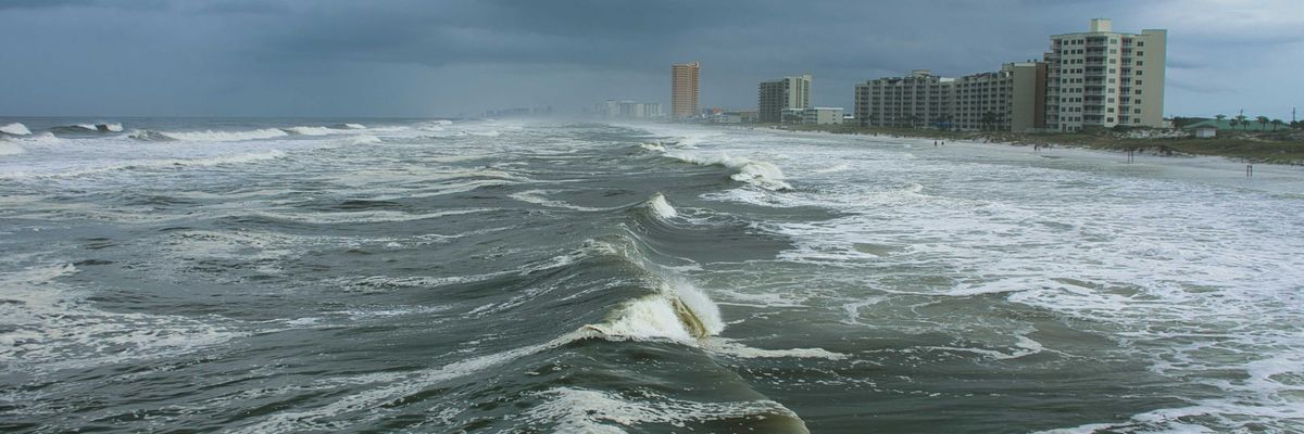 ocean waves near city buildings during daytime