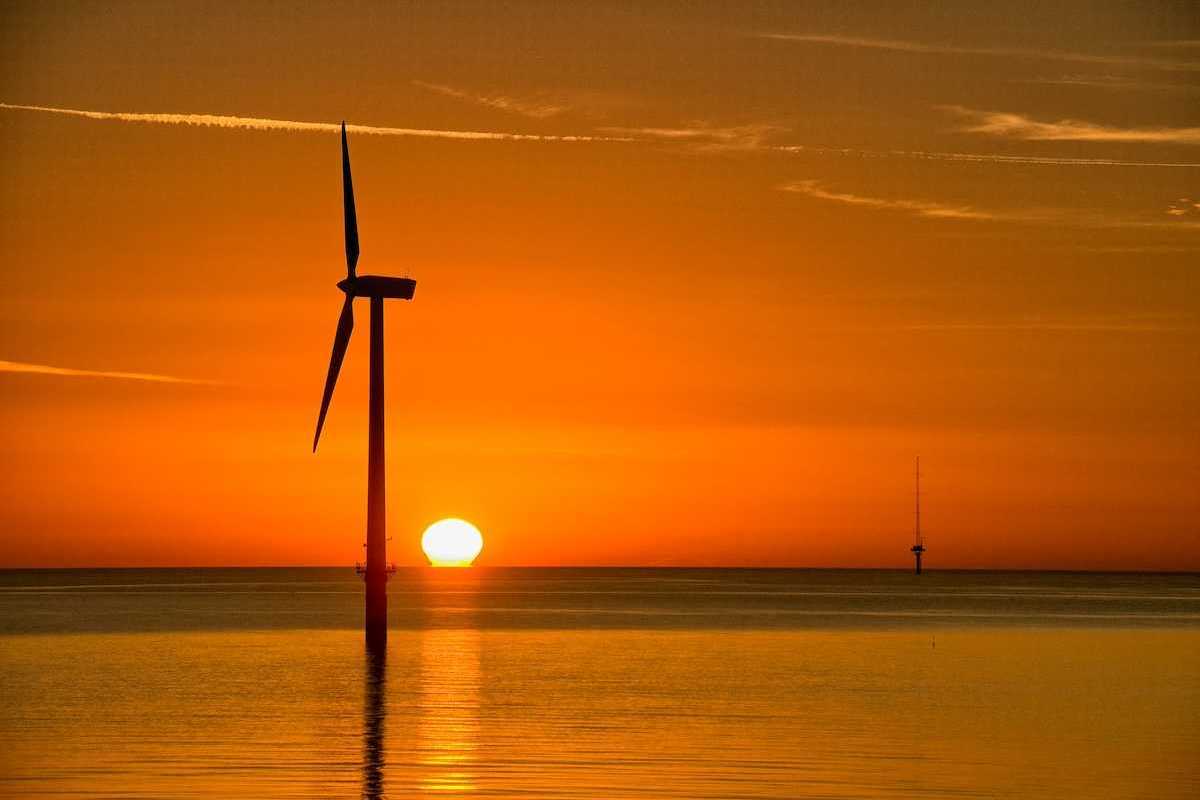 Offshore wind turbine silouetted against setting sun