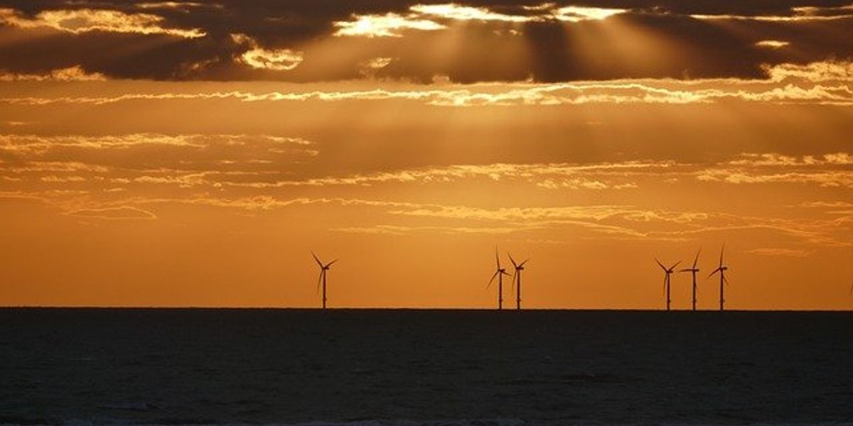Offshore wind turbines under a sunset.
