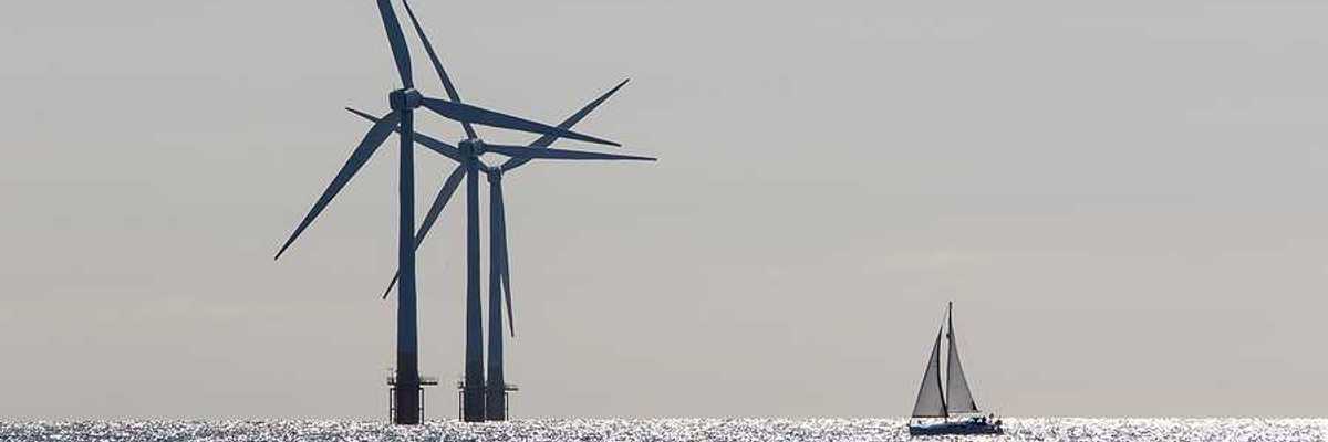 Offshore wind turbines with a sailboat in the foreground