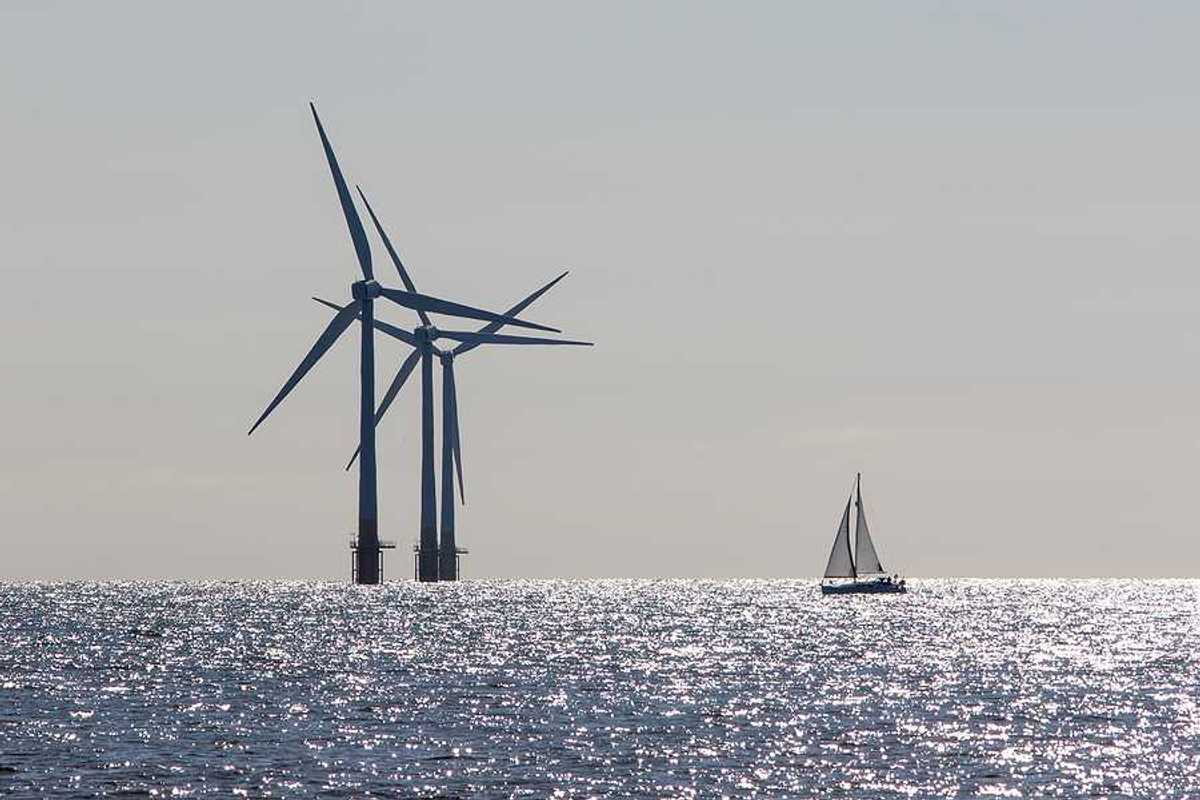 Offshore wind turbines with a sailboat in the foreground
