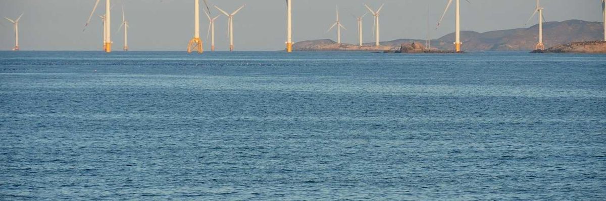 Offshore wind turbines with beachgoers in foreground