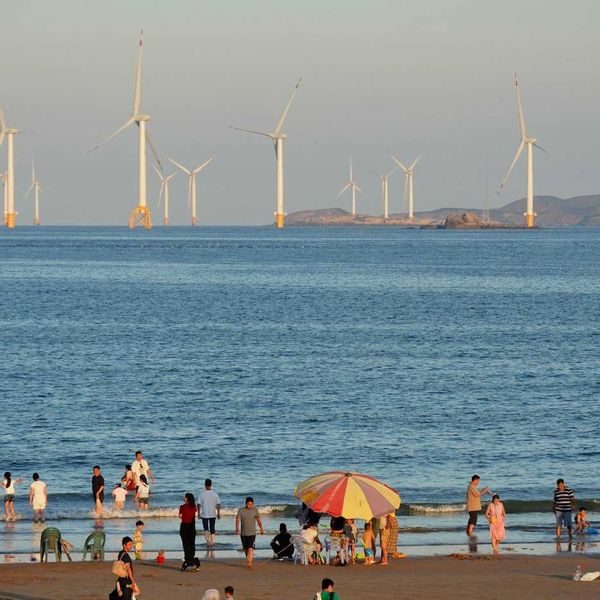 Offshore wind turbines with beachgoers in foreground