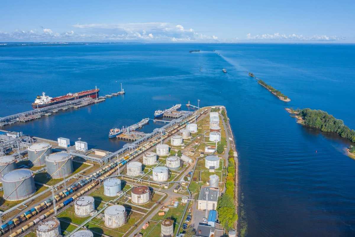 Oil and gas export terminal tanker at dock and multiple storage tanks adjacent to a large waterbody