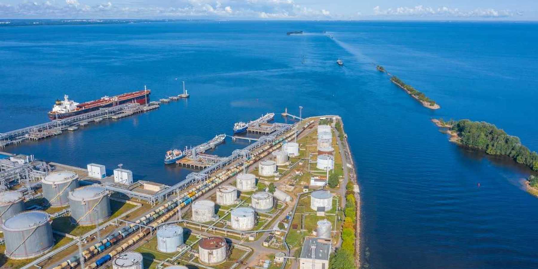 Oil and gas export terminal tanker at dock and multiple storage tanks adjacent to a large waterbody