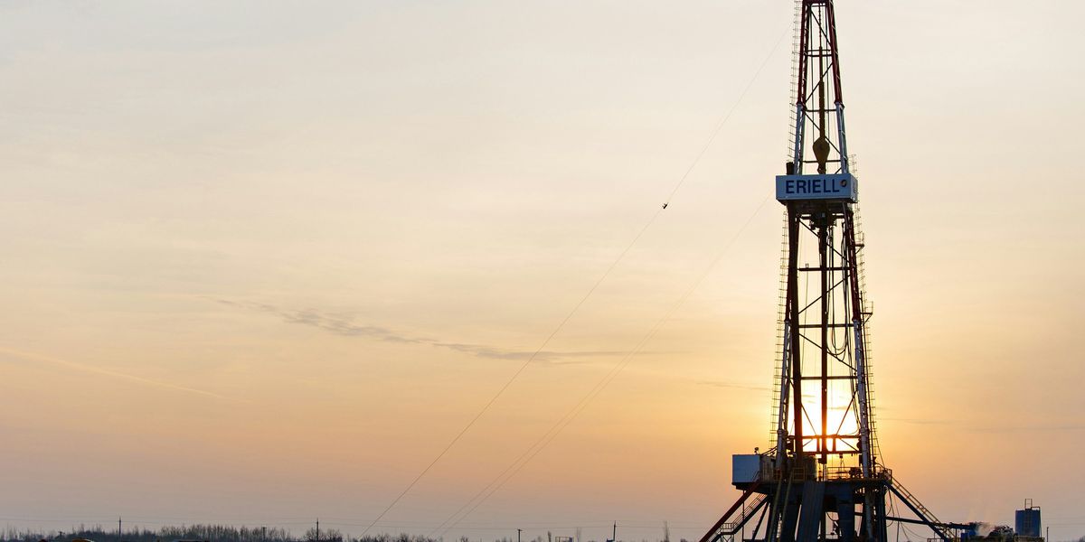 Oil drilling equipment in a field at sunset.