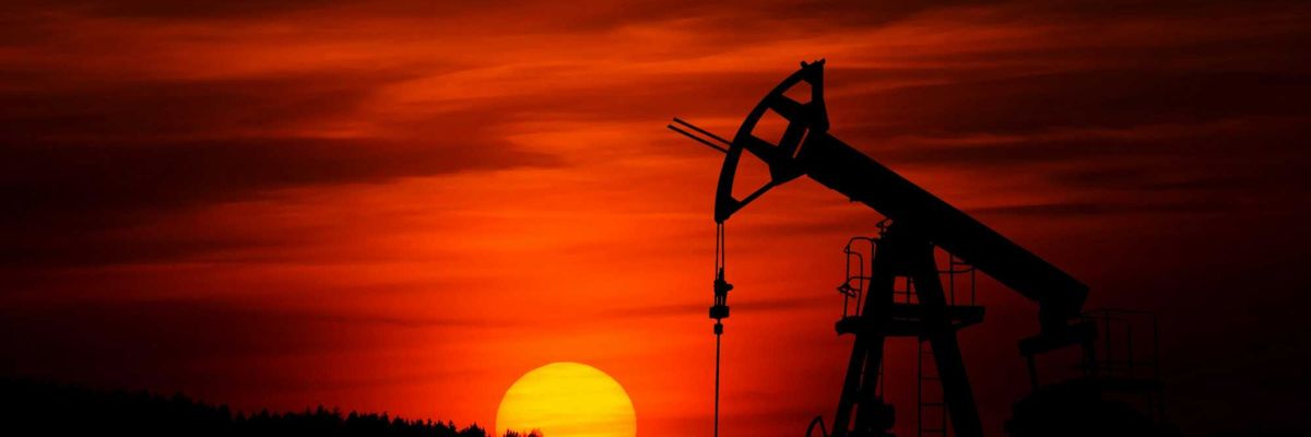 Oil drilling rig silhouetted against a red sunset sky.