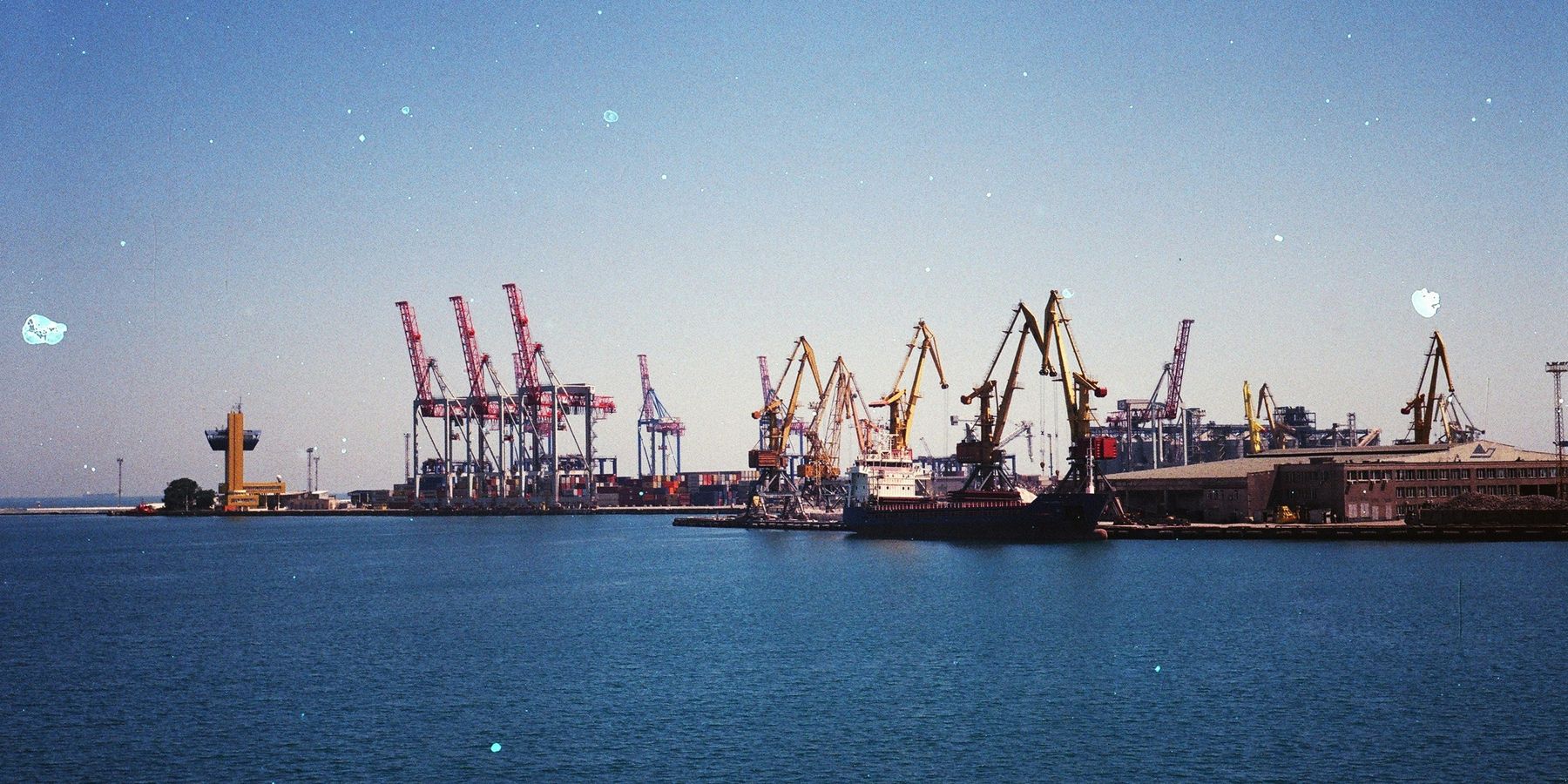 Oil export ships and cranes at a dock in the daytime.