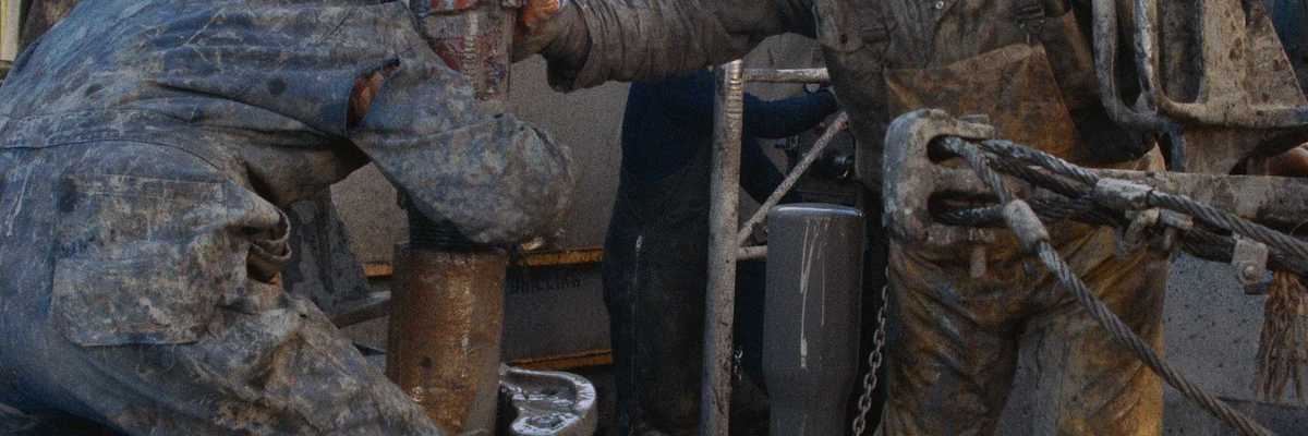 Oil field workers manipulating a drilling rig