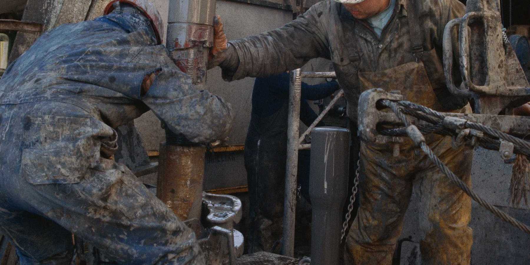 Oil field workers manipulating a drilling rig