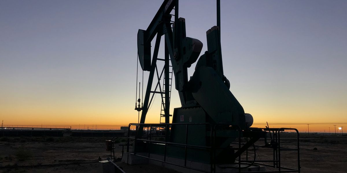 Oil pump jack in silhouette with the sunset in the background