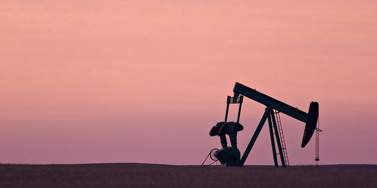 Oil pump jack silhouetted against a pink and violet sky.