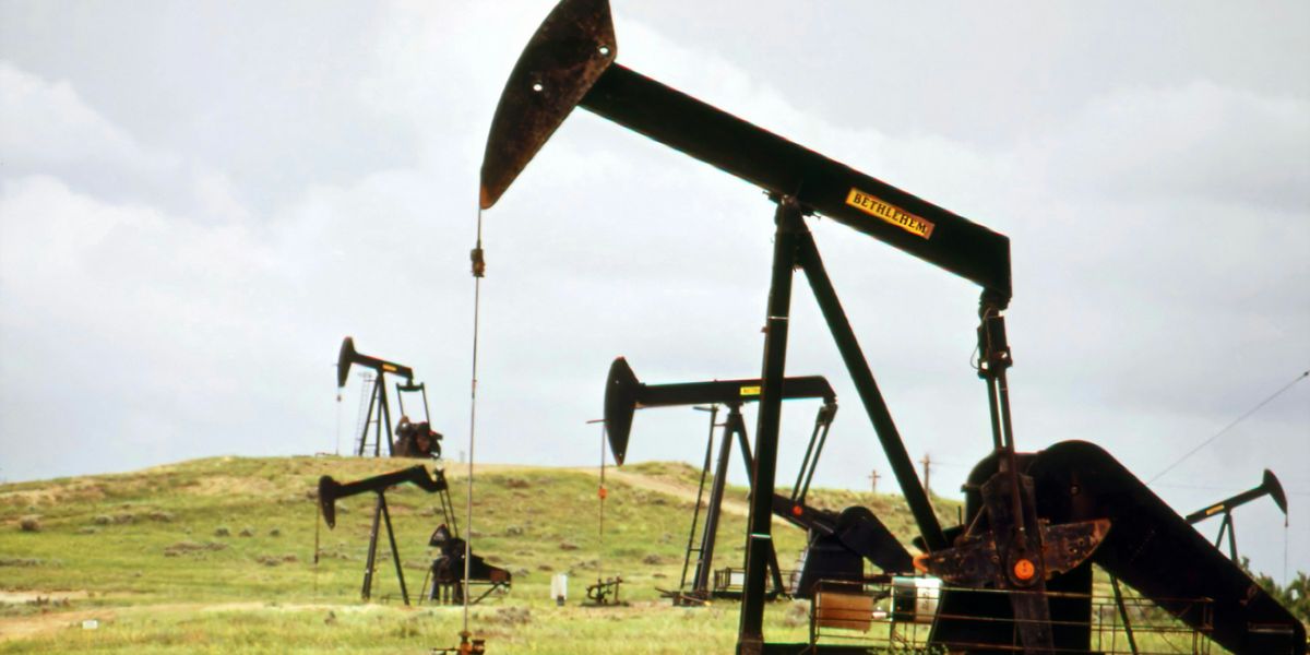 Oil pumps sitting on a green field.