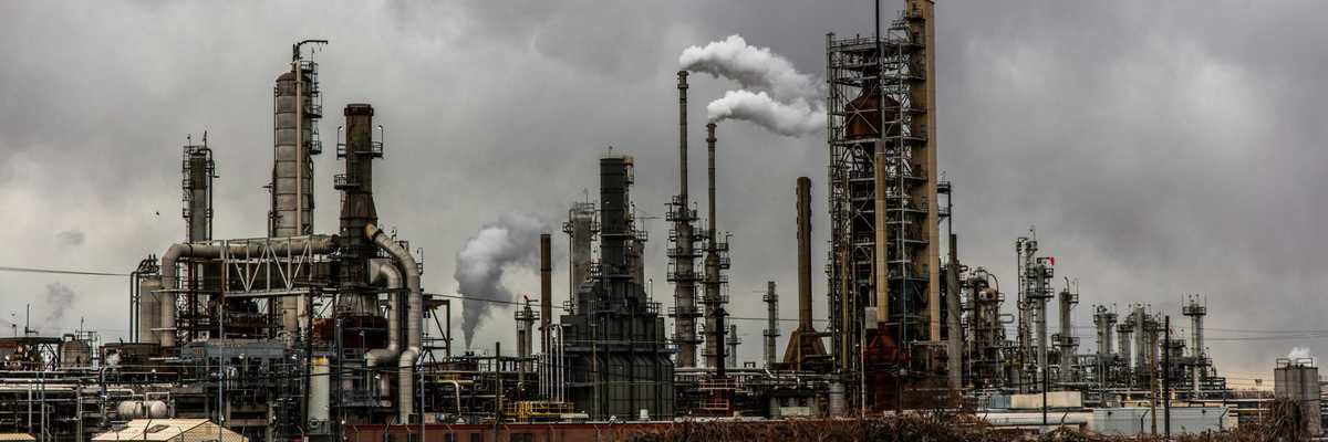 oil refinery emitting pollution under cloudy sky.