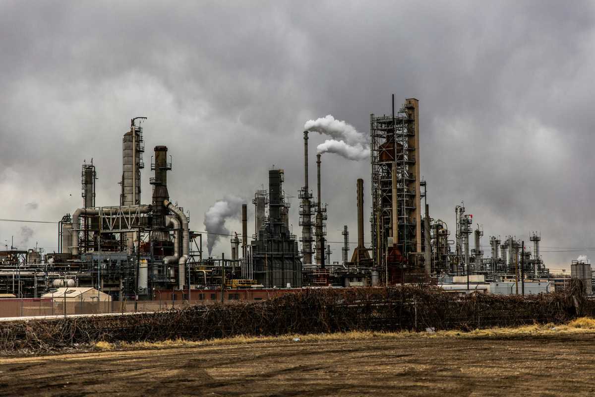 oil refinery emitting pollution under cloudy sky.