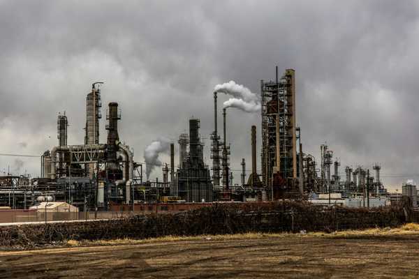 oil refinery emitting pollution under cloudy sky.