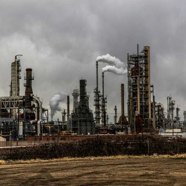 oil refinery emitting pollution under cloudy sky.