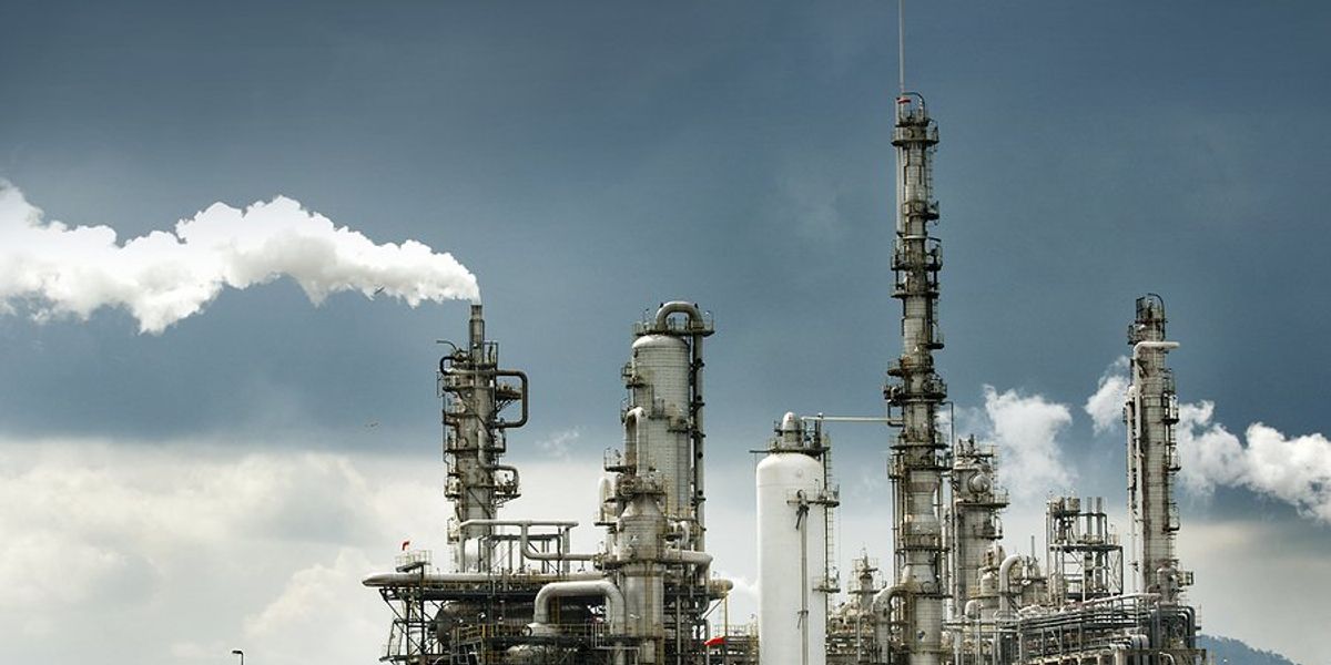 Oil refinery with smoke billowing from smokestacks.