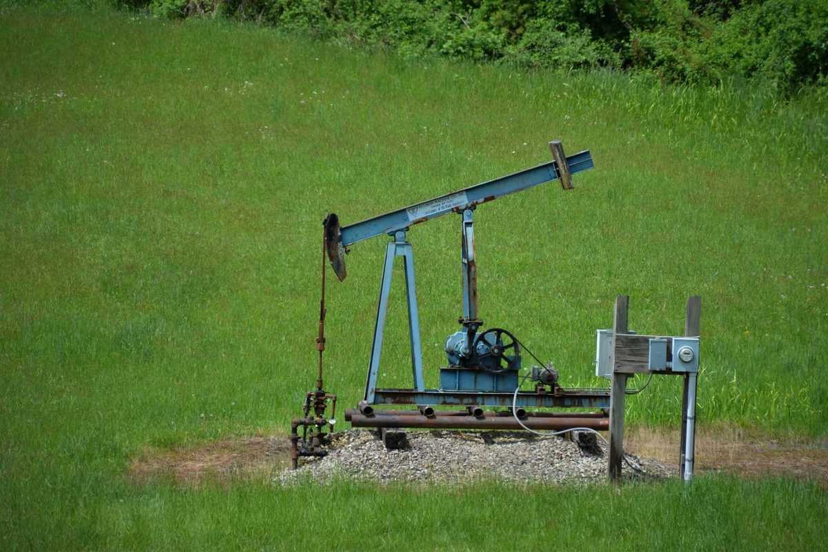 Old oil pump jack in a grassy green field.