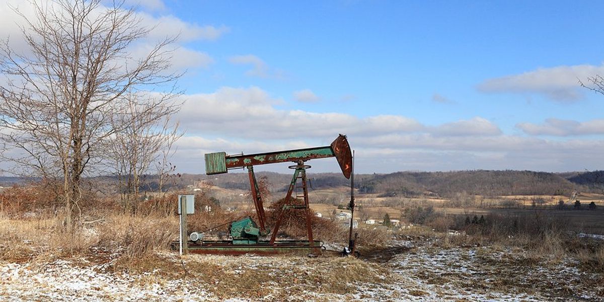 Old rusty oil drilling equipment in the middle of an icy field.