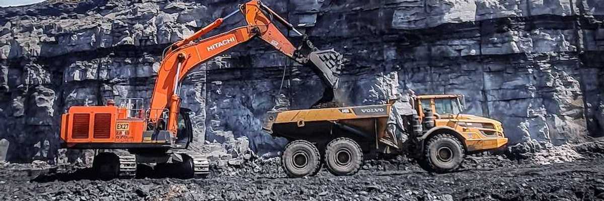 Orange excavator loading yellow rock truck at coal mine