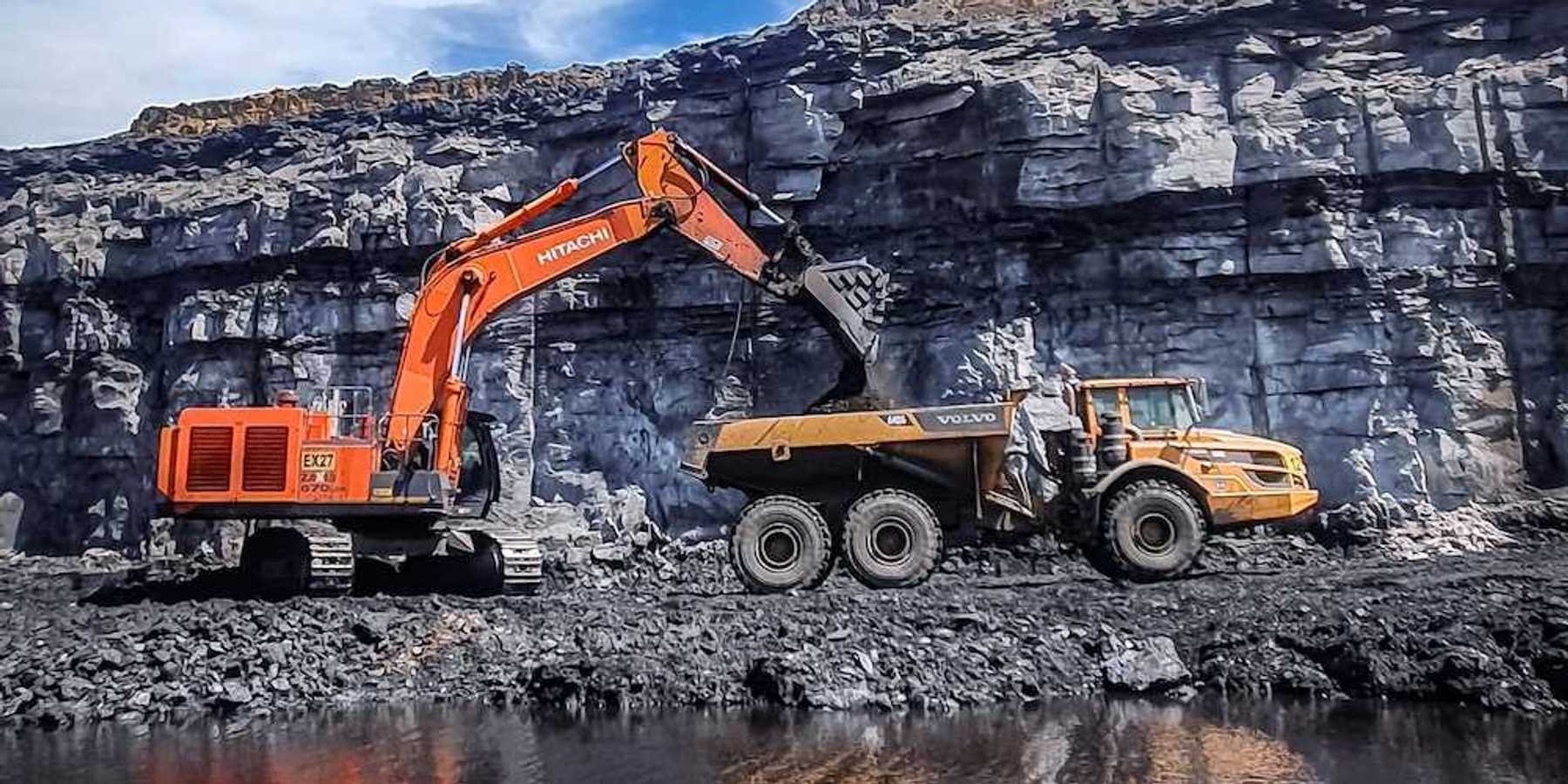 Orange excavator loading yellow rock truck at coal mine