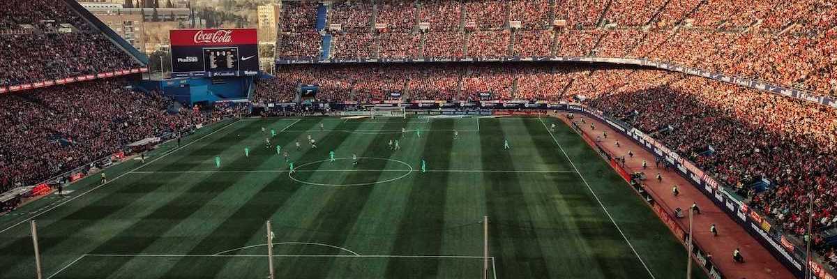 Packed soccer stadium with signage advertising various corporate sponsors