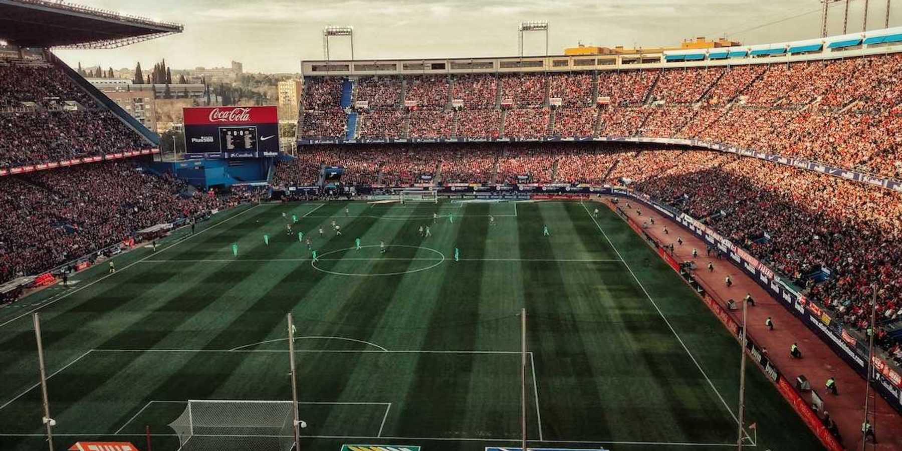 Packed soccer stadium with signage advertising various corporate sponsors