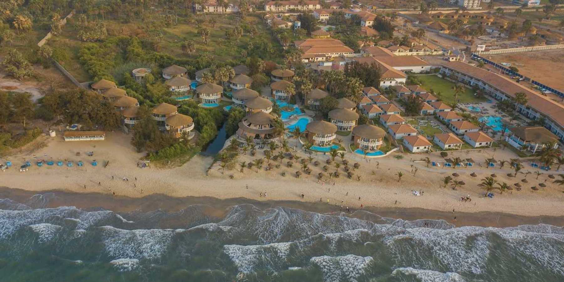 Panoramic drone view of Balafon Beach Resort on Kololi Beach in Gambia shows close proximity of ocean and inland residences