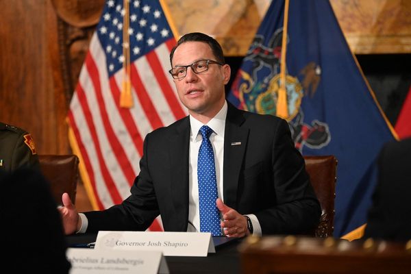 Pennsylvania governor Josh Shapiro speaks with the state flag and American flag behind him.