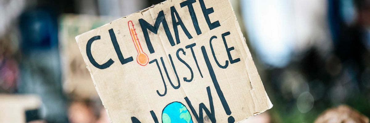 people gathered outside buildings holding Climate Justice Now signage.