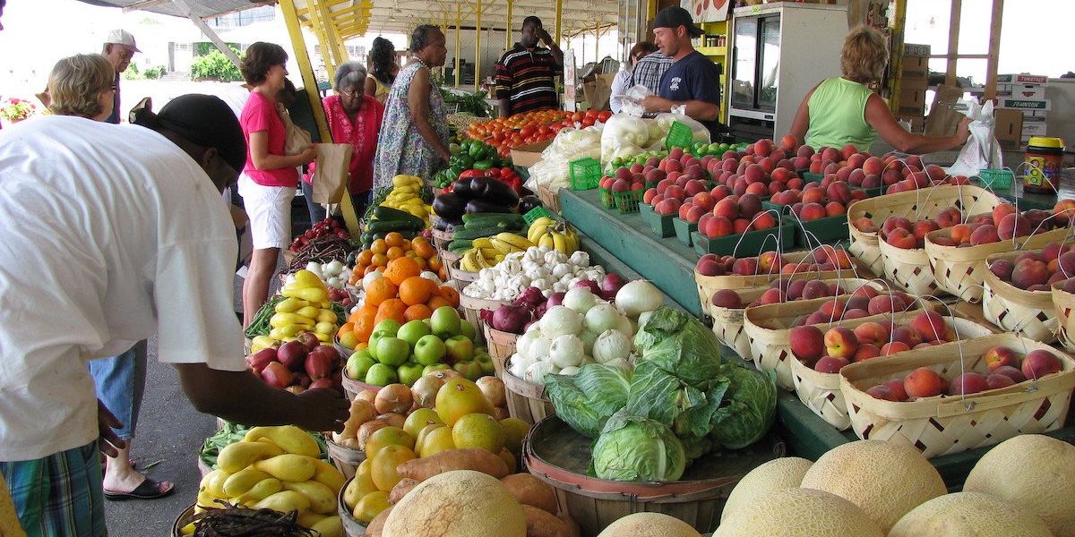 People shop for produce at a farmers market.