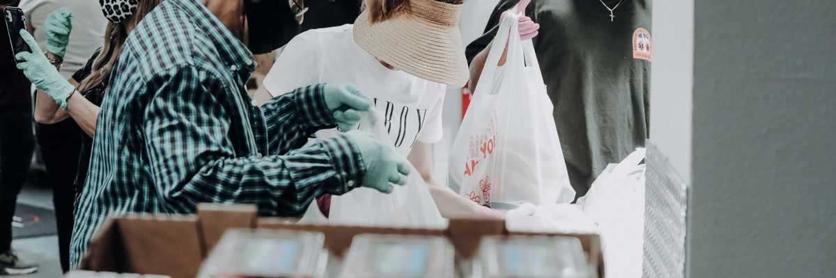 people standing in front of brown cardboard boxes of strawberries.