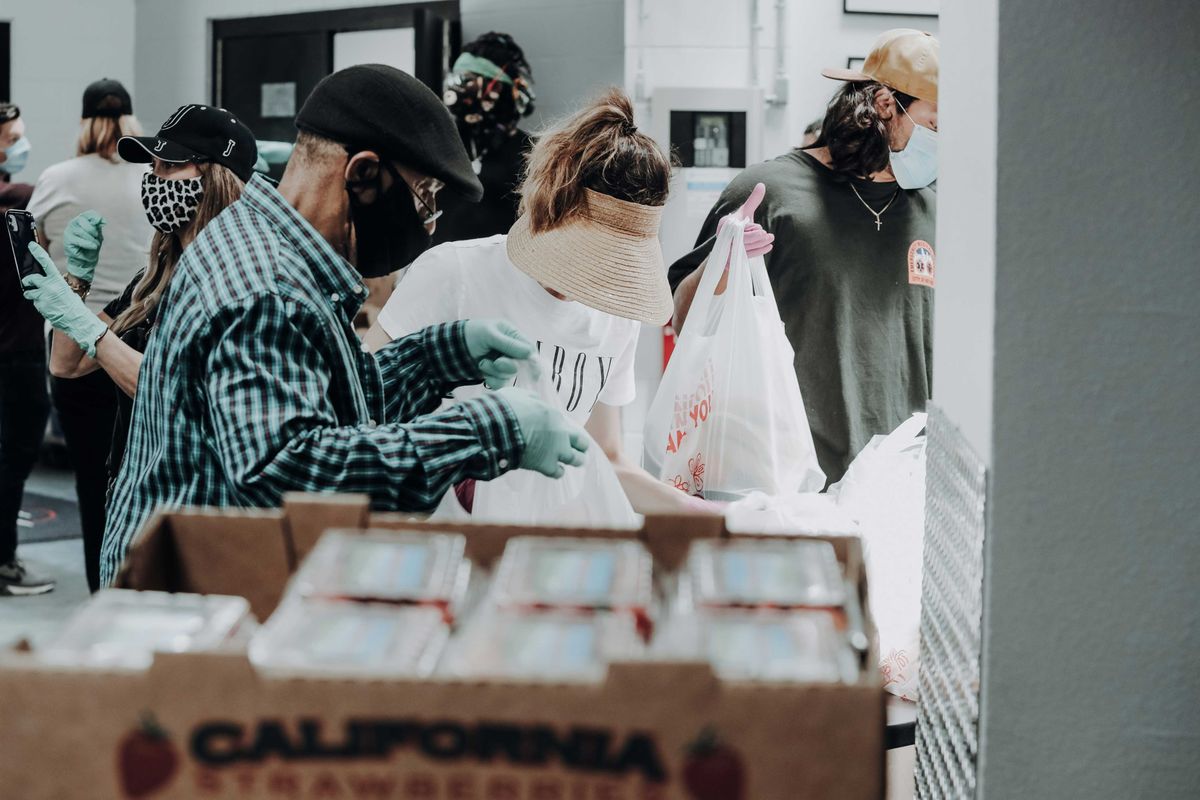 people standing in front of brown cardboard boxes of strawberries.