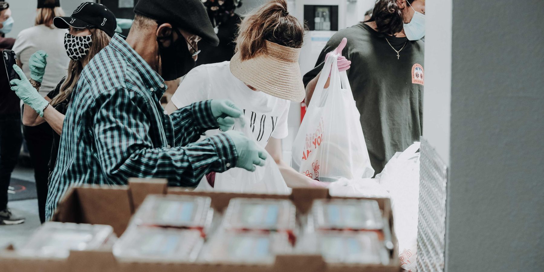 people standing in front of brown cardboard boxes of strawberries.