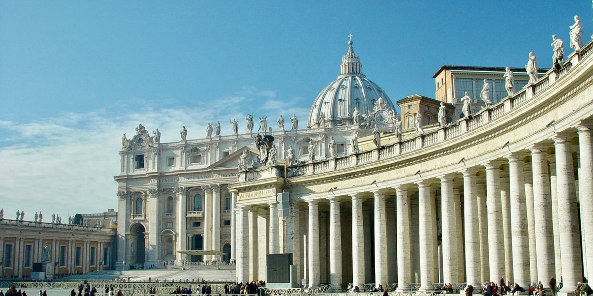 People walking around the Vatican buildings during daytime.