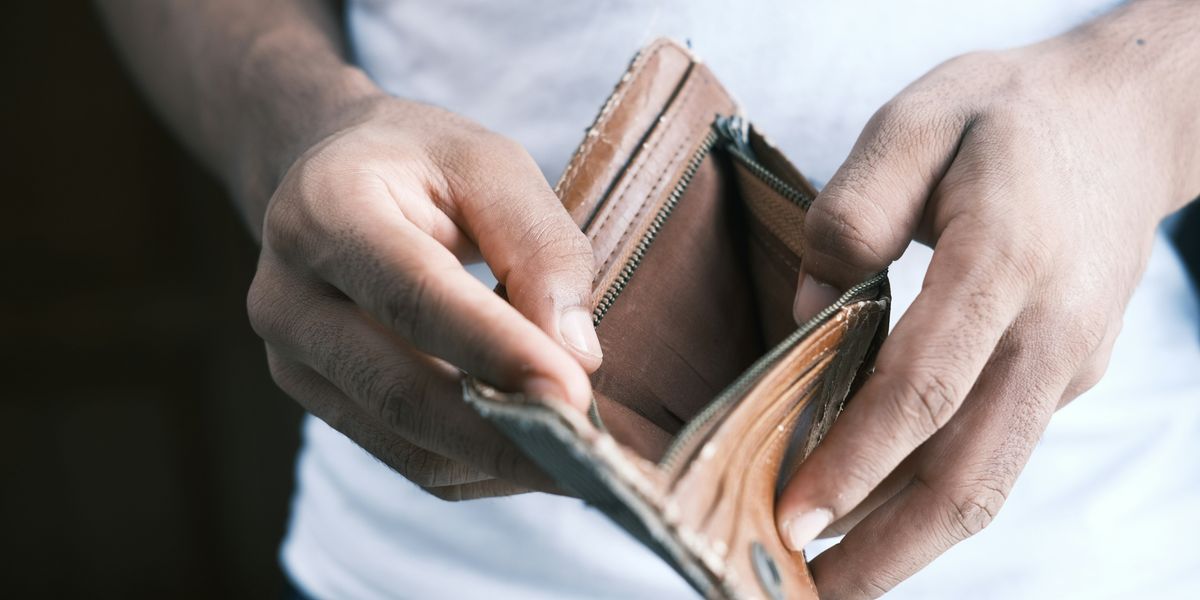 person holding empty brown leather bifold wallet.