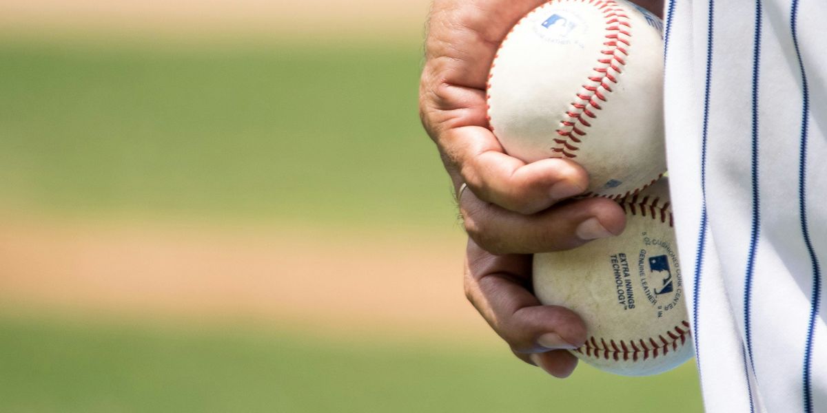 person holding two baseballs