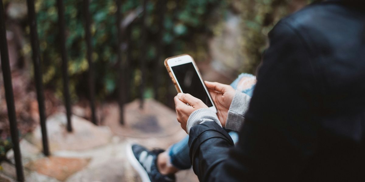 person holding white smartphone sitting on stair