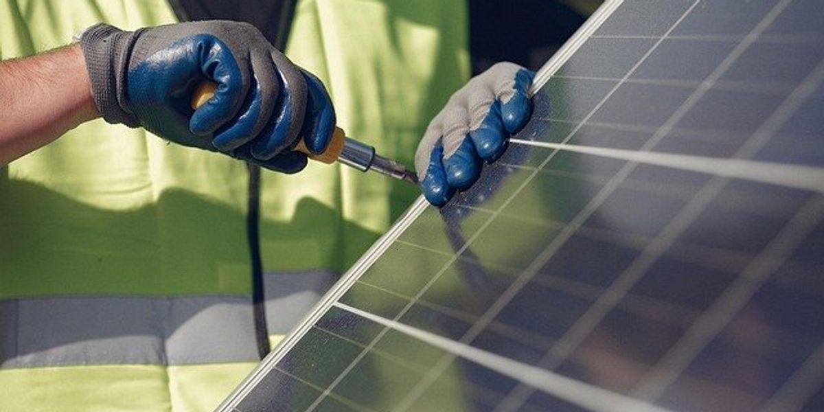 Person in a yellow vest installing a solar panel
