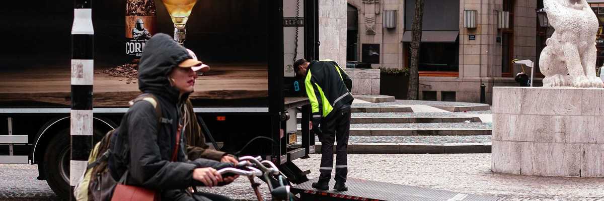 Person rides bicycle past truck with beer advertisement