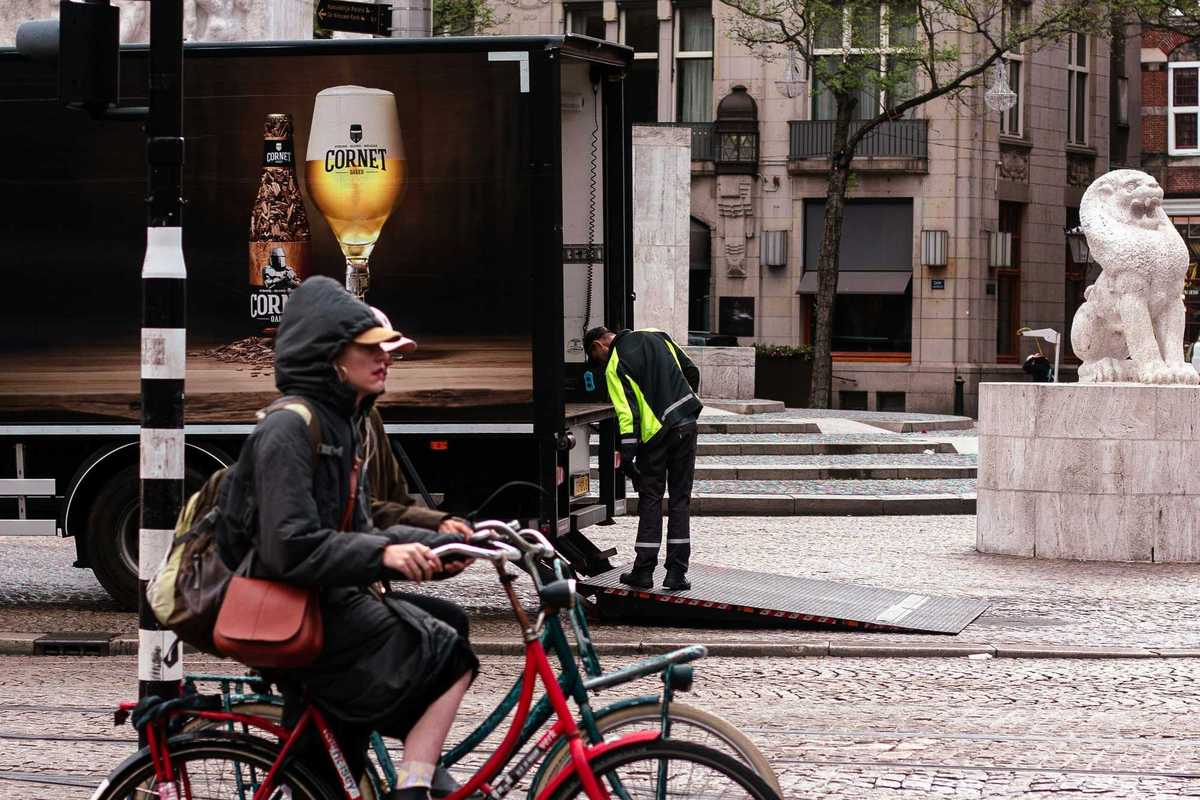 Person rides bicycle past truck with beer advertisement