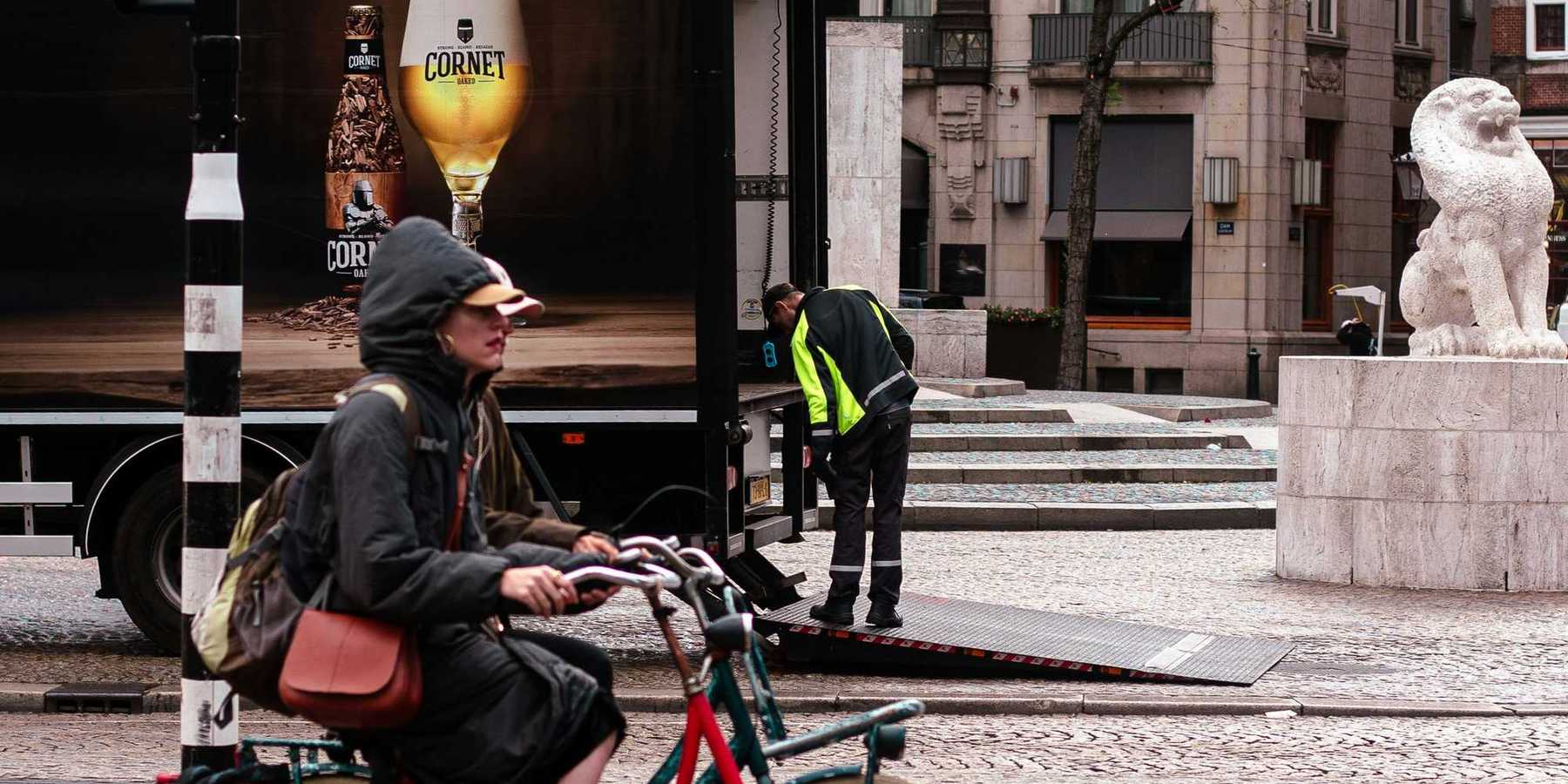 Person rides bicycle past truck with beer advertisement